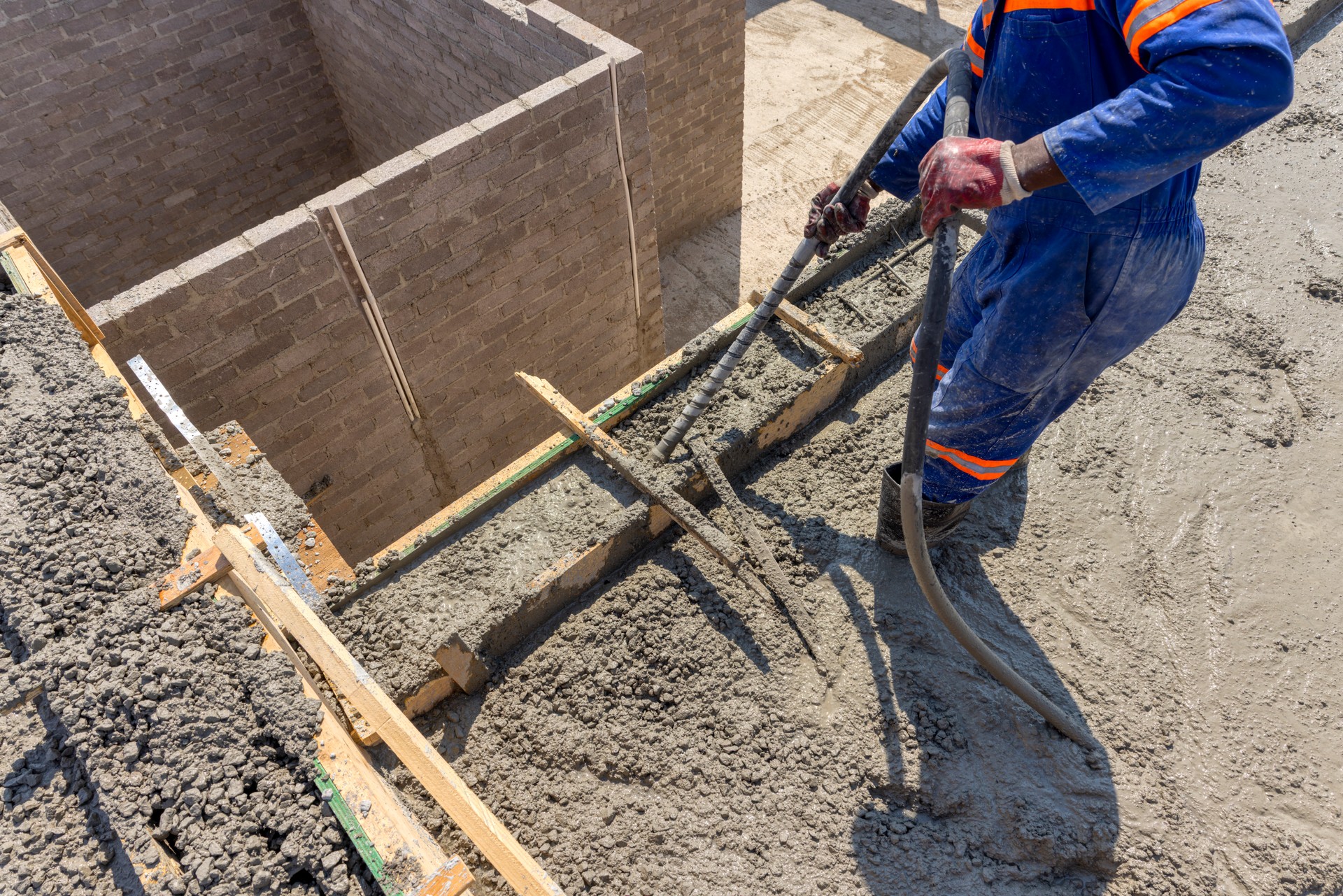 boom concrete pump, pouring concrete on the top floor african worker operating the vibrating rubber pipe