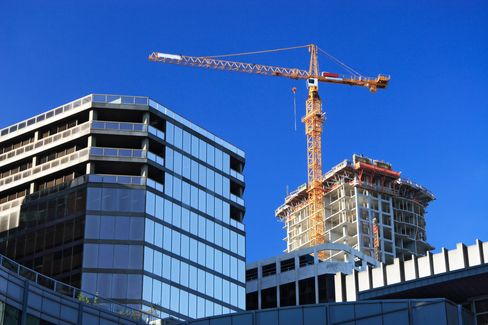 Tall orange crane towering over glass building